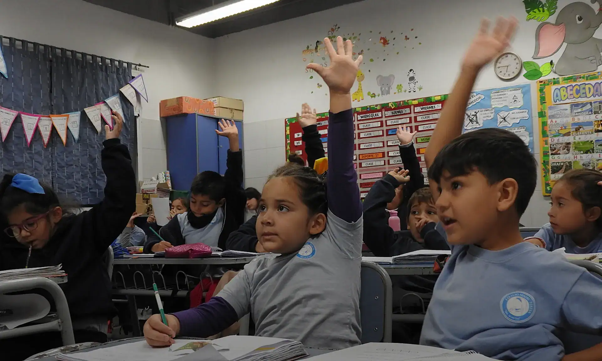Elementary students raising their hands in class